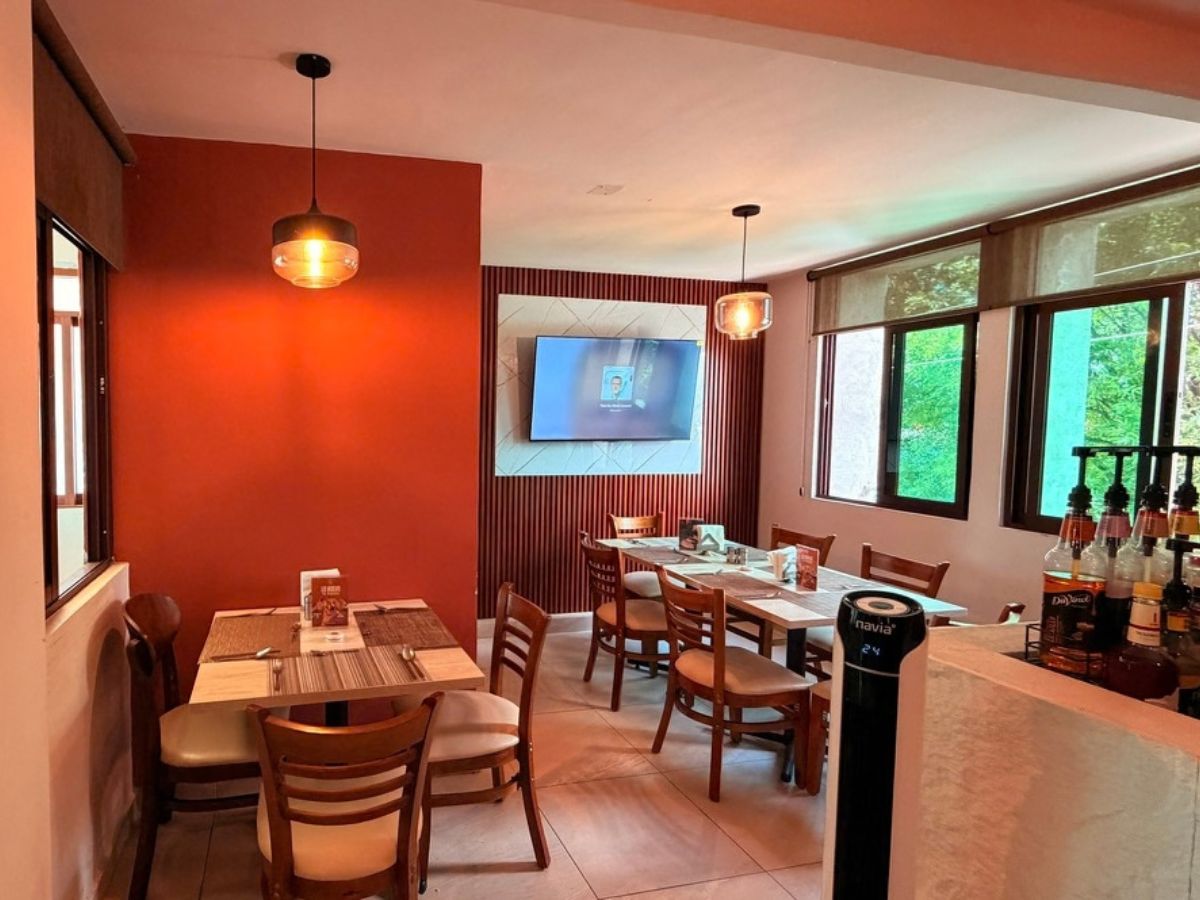 Salón de la cafetería con lámparas cálidas y mesas listas