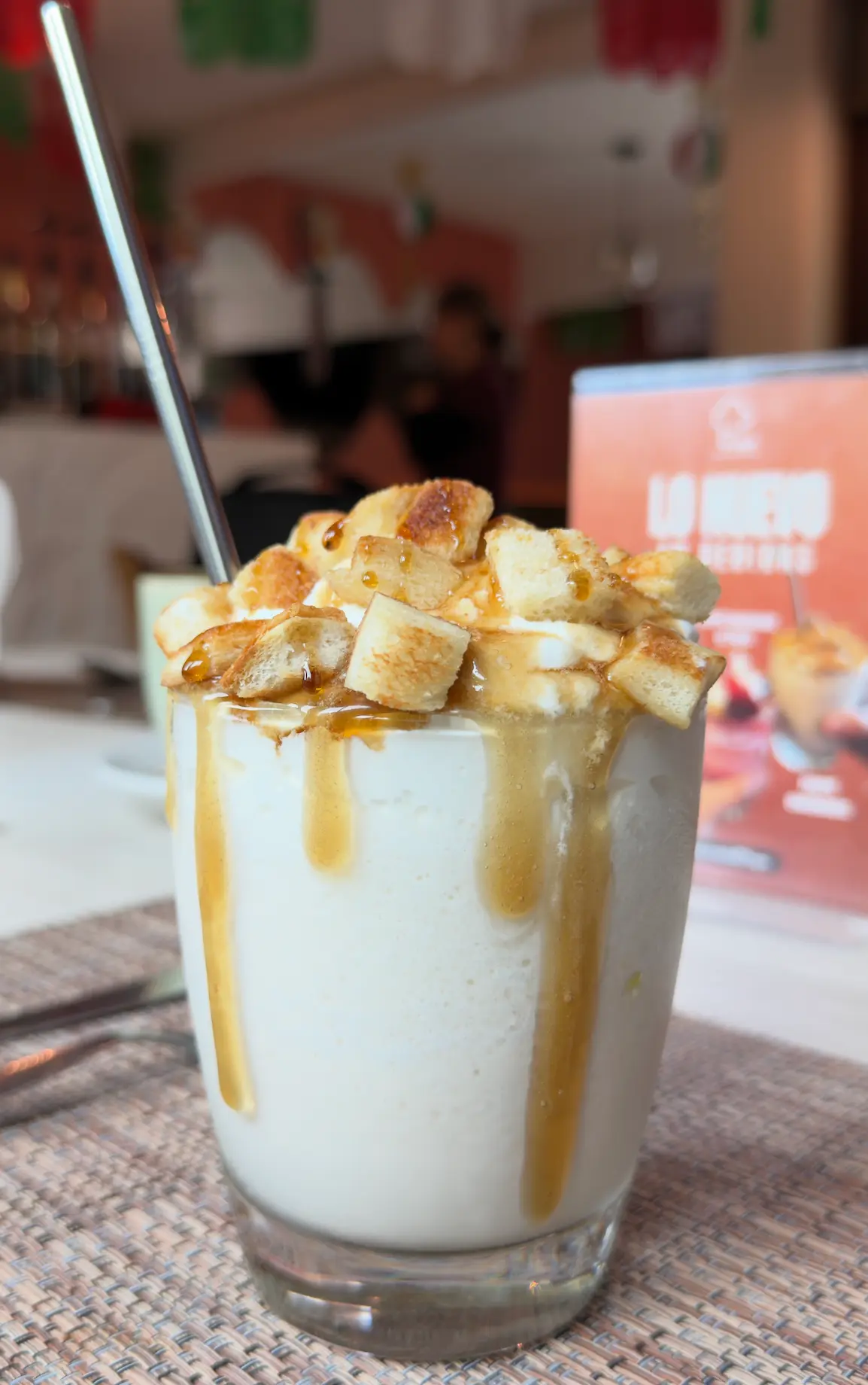 Bebida cremosa con cajeta y trozos de pan tostado en vaso
